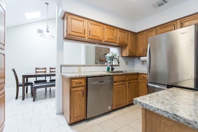 kitchen with stainless steel appliances, sink, backsplash, and light stone counters