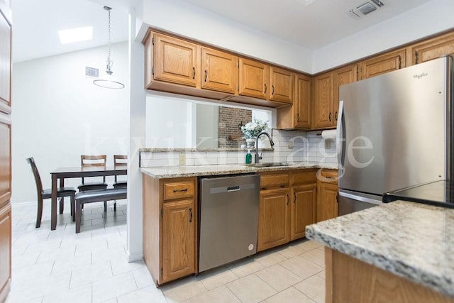 kitchen with light stone counters, appliances with stainless steel finishes, sink, and tasteful backsplash