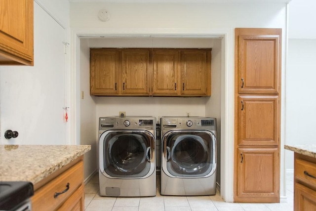 washroom with washer and clothes dryer, cabinets, and light tile patterned flooring