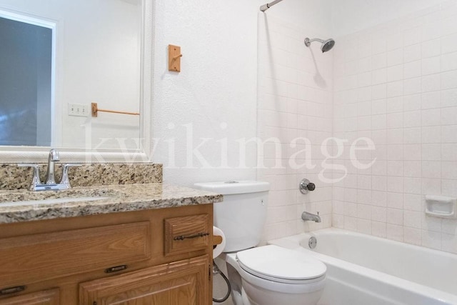 full bathroom featuring vanity, tiled shower / bath combo, and toilet