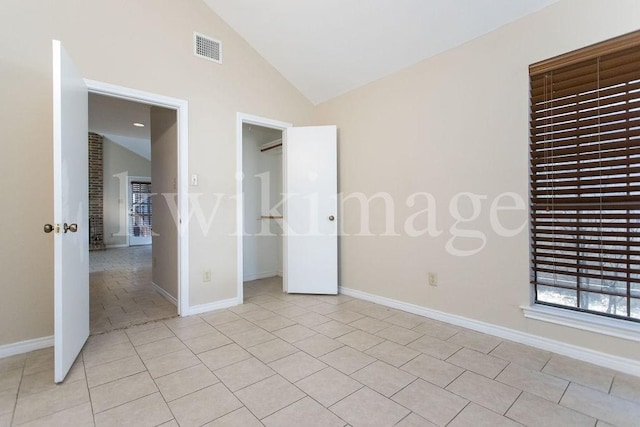 unfurnished bedroom with light tile patterned flooring and high vaulted ceiling