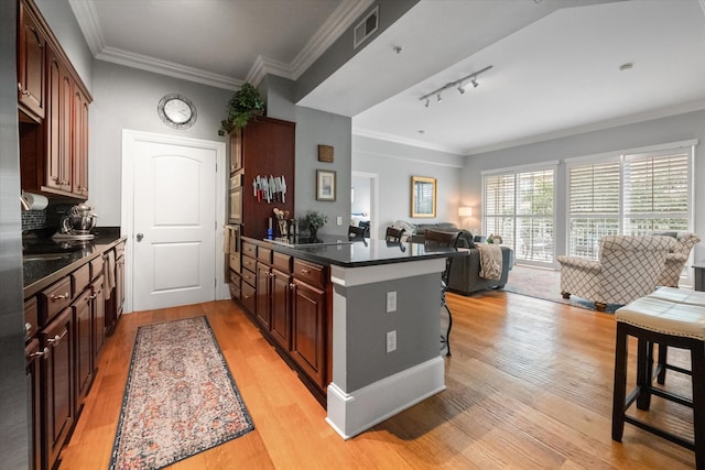 kitchen with a breakfast bar, crown molding, dark brown cabinets, light wood-type flooring, and kitchen peninsula