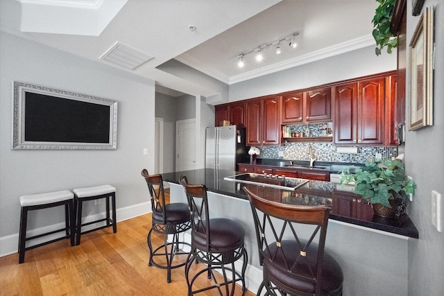 kitchen with stainless steel refrigerator, sink, decorative backsplash, black electric stovetop, and light hardwood / wood-style floors