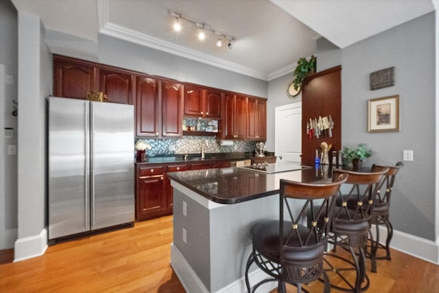 kitchen with sink, stainless steel fridge, light hardwood / wood-style flooring, a kitchen breakfast bar, and tasteful backsplash