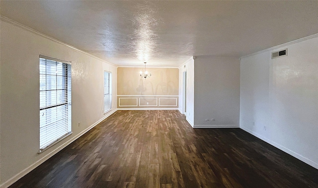 empty room with ornamental molding, an inviting chandelier, a textured ceiling, and dark hardwood / wood-style flooring