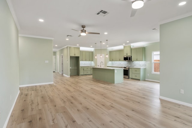 kitchen featuring appliances with stainless steel finishes, decorative backsplash, hanging light fixtures, a kitchen island with sink, and crown molding