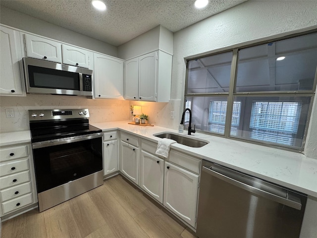 kitchen featuring sink, light wood-type flooring, white cabinets, and appliances with stainless steel finishes