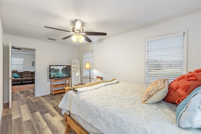 bedroom with ornamental molding, dark hardwood / wood-style floors, and ceiling fan