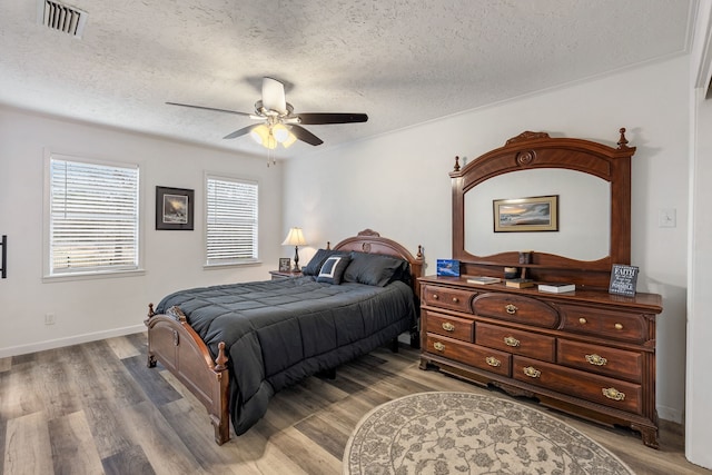 bedroom featuring hardwood / wood-style flooring, ceiling fan, and a textured ceiling