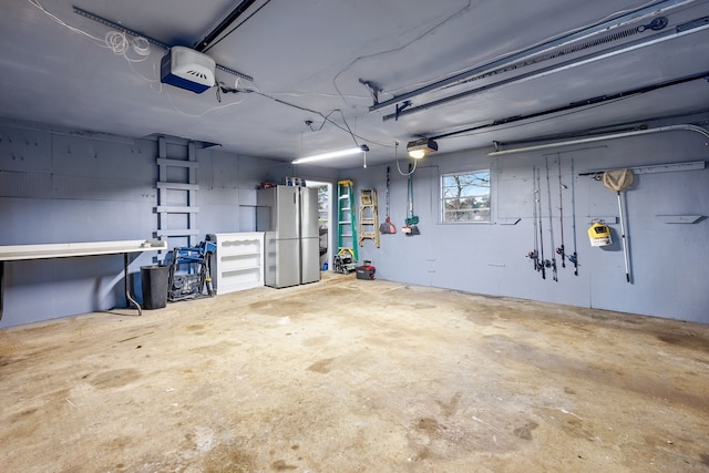 garage with a garage door opener and stainless steel fridge