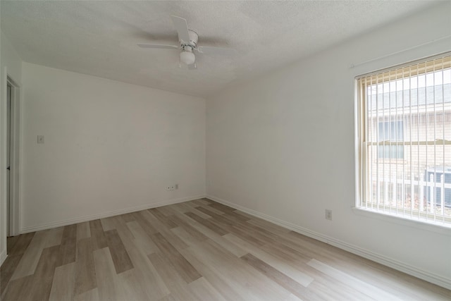 spare room featuring a textured ceiling, a wealth of natural light, ceiling fan, and light wood-type flooring