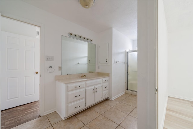 bathroom featuring tile patterned floors, vanity, and a shower with door