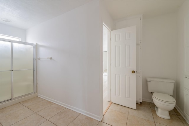 bathroom with toilet, an enclosed shower, and tile patterned flooring