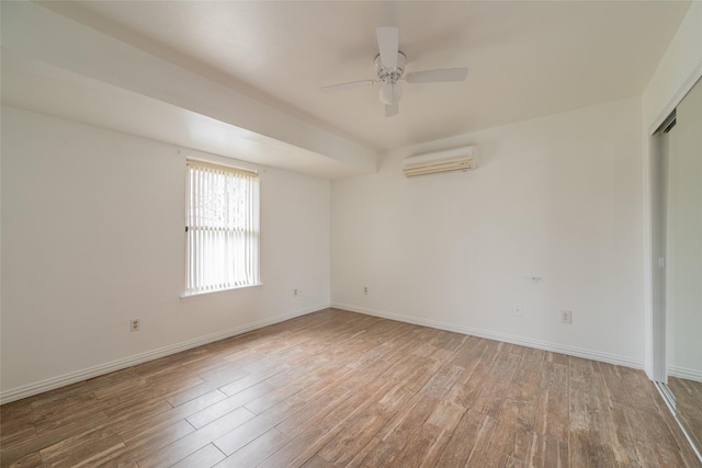 spare room with ceiling fan, a wall unit AC, and light hardwood / wood-style flooring