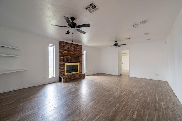 unfurnished living room with crown molding, ceiling fan, dark hardwood / wood-style floors, a textured ceiling, and a brick fireplace