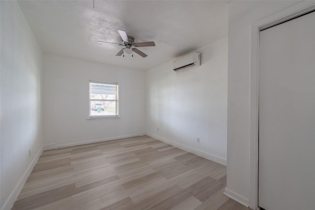 empty room featuring ceiling fan, light hardwood / wood-style flooring, and an AC wall unit