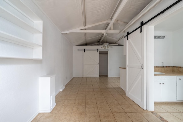 hallway featuring a barn door, light tile patterned floors, and lofted ceiling