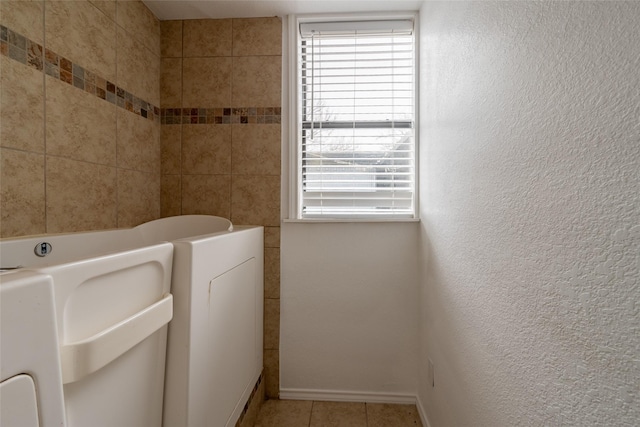 clothes washing area with light tile patterned floors and a wealth of natural light