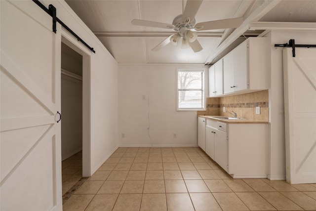 kitchen featuring white cabinetry, sink, a barn door, and ceiling fan