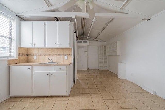 kitchen featuring sink, vaulted ceiling with beams, white cabinets, and decorative backsplash