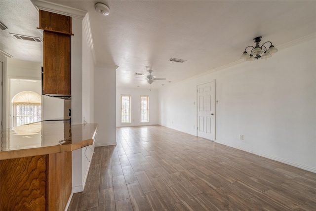 unfurnished living room with wood-type flooring, ceiling fan with notable chandelier, and crown molding