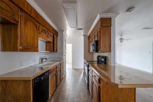 kitchen with sink, ornamental molding, kitchen peninsula, hardwood / wood-style floors, and black appliances