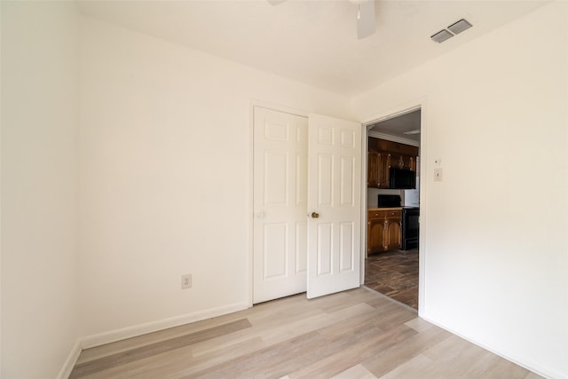 spare room with ceiling fan and light wood-type flooring