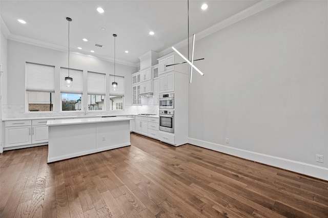 kitchen with white cabinetry, crown molding, hanging light fixtures, and hardwood / wood-style flooring