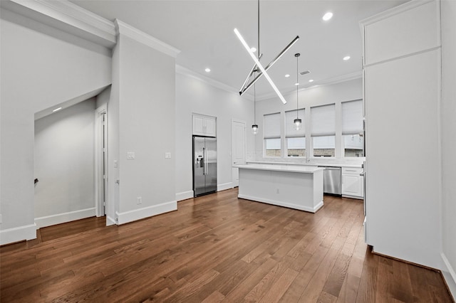 kitchen featuring pendant lighting, stainless steel appliances, a center island, wood-type flooring, and white cabinets