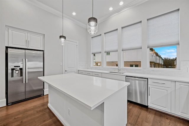 kitchen featuring decorative light fixtures, sink, white cabinets, a center island, and stainless steel appliances