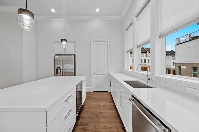 kitchen with white cabinetry, appliances with stainless steel finishes, decorative light fixtures, and sink