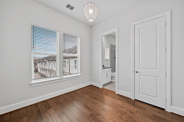 unfurnished bedroom with dark wood-type flooring and connected bathroom