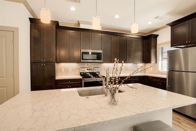 kitchen featuring tasteful backsplash, appliances with stainless steel finishes, and hanging light fixtures