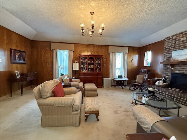 living room featuring wood walls, a chandelier, carpet, a brick fireplace, and a textured ceiling