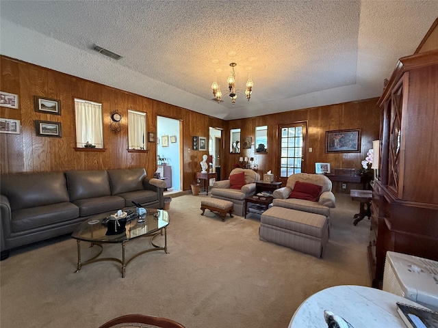 living room featuring carpet, a textured ceiling, and an inviting chandelier