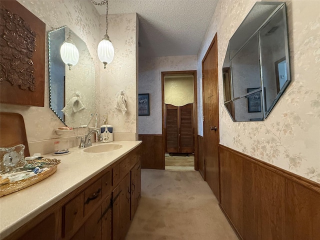 bathroom with vanity, a textured ceiling, and wood walls