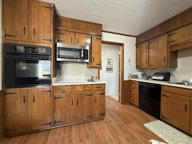 kitchen featuring tasteful backsplash, sink, light hardwood / wood-style flooring, and black appliances