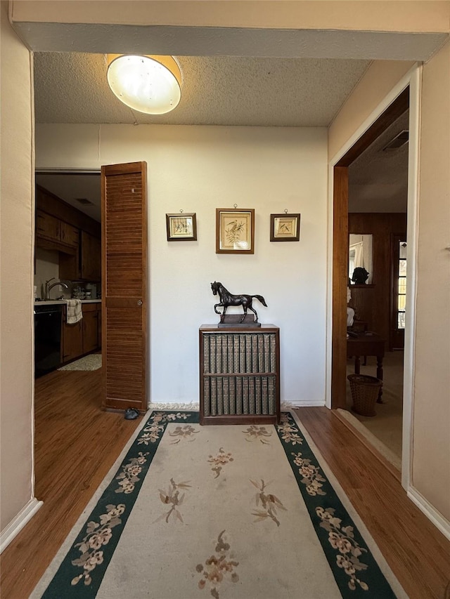 corridor with wood-type flooring and a textured ceiling