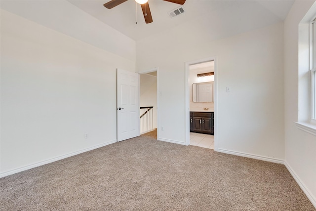 unfurnished bedroom featuring light carpet, connected bathroom, sink, and ceiling fan