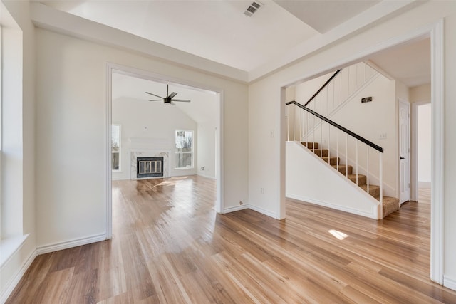 unfurnished living room featuring lofted ceiling, hardwood / wood-style floors, a premium fireplace, and ceiling fan