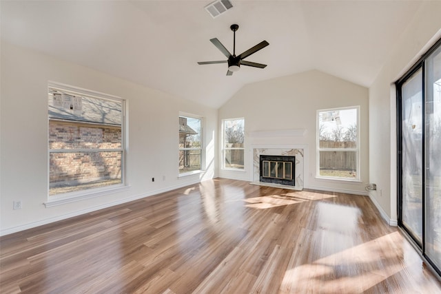 unfurnished living room with lofted ceiling, a fireplace, light hardwood / wood-style floors, and a healthy amount of sunlight