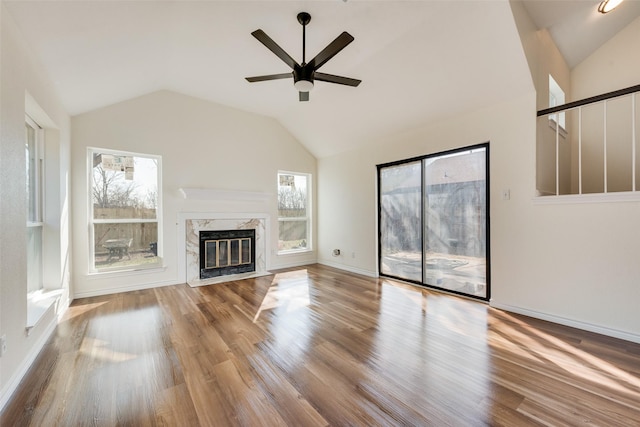 unfurnished living room with ceiling fan, lofted ceiling, a fireplace, and hardwood / wood-style floors