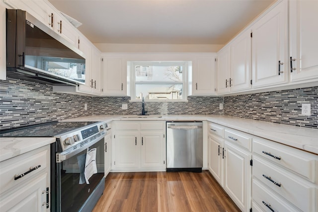 kitchen with sink, dark wood-type flooring, white cabinetry, stainless steel appliances, and light stone counters