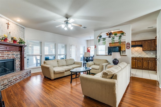 living room with ceiling fan, hardwood / wood-style floors, and a fireplace