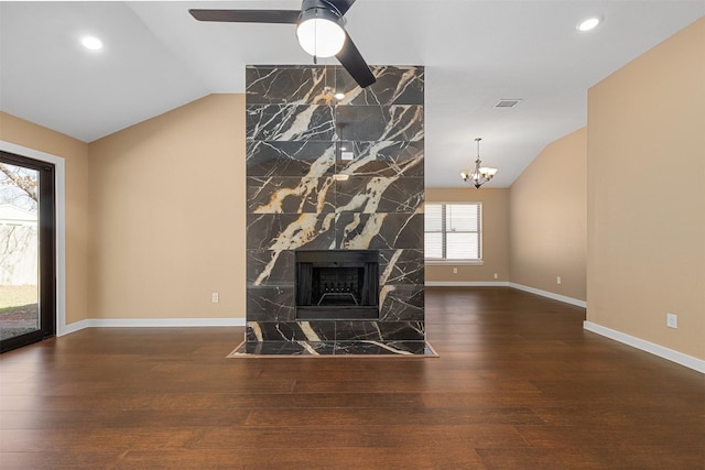 unfurnished living room featuring vaulted ceiling, a high end fireplace, ceiling fan with notable chandelier, and dark hardwood / wood-style flooring