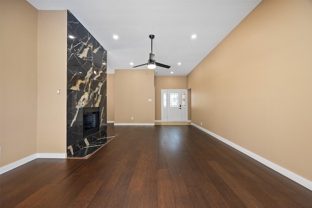 unfurnished living room with a premium fireplace, dark hardwood / wood-style floors, and ceiling fan