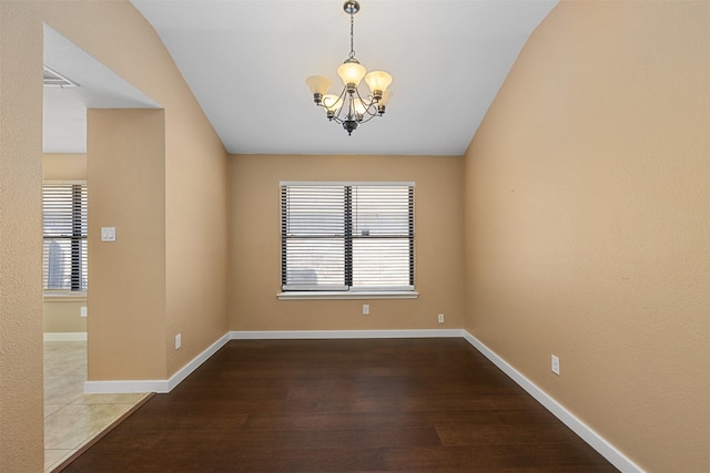 unfurnished room with hardwood / wood-style flooring and an inviting chandelier