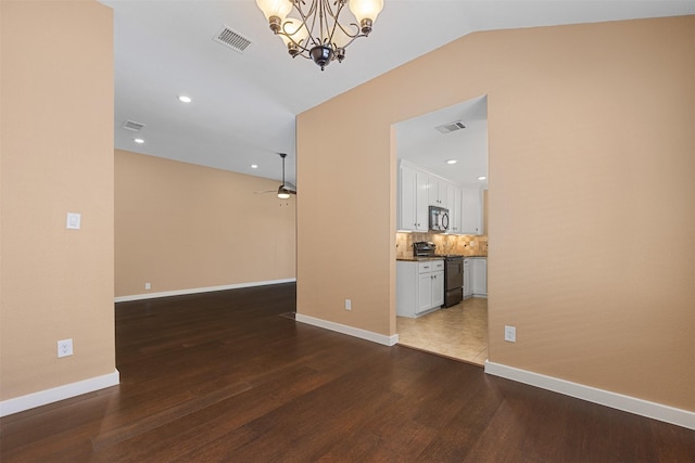 spare room featuring hardwood / wood-style flooring, lofted ceiling, and ceiling fan with notable chandelier