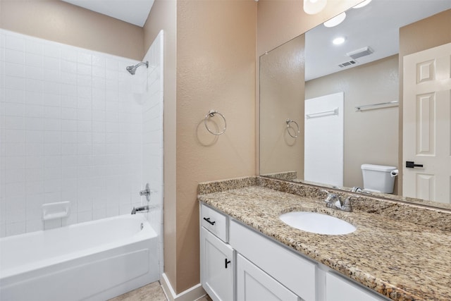 full bathroom featuring tiled shower / bath, vanity, and toilet