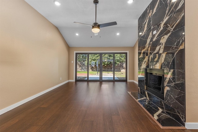 unfurnished living room featuring a premium fireplace, lofted ceiling, dark wood-type flooring, and ceiling fan